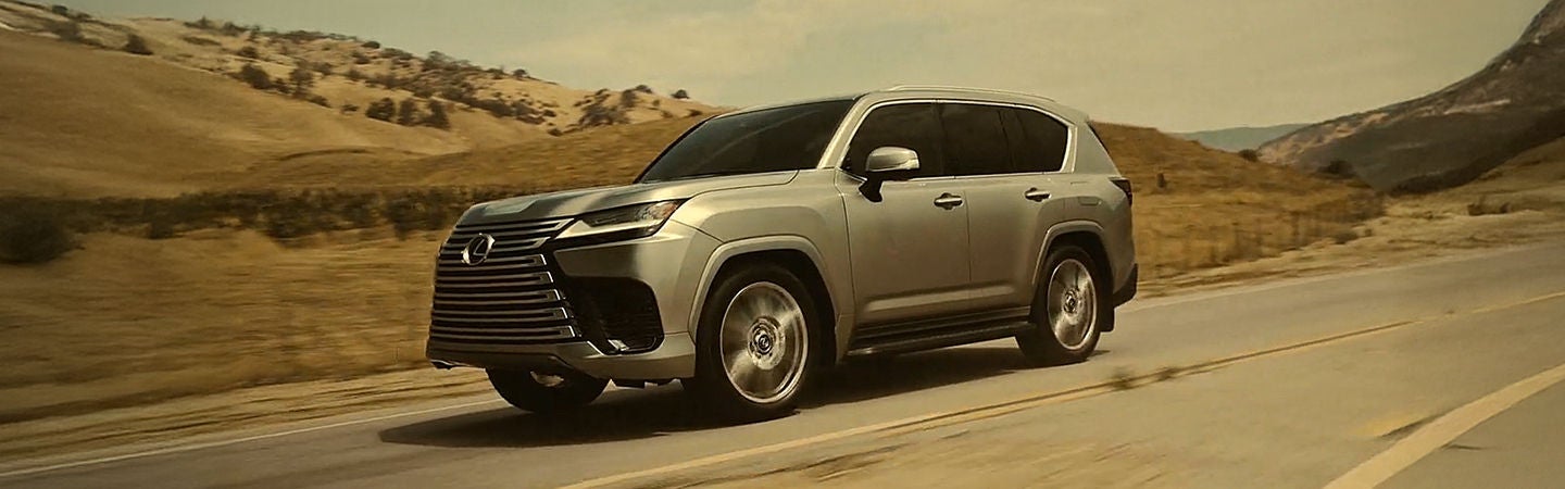 Silver Lexus SUV driving on a road through golden hills. Text: Benefits & Destinations by Lexus.