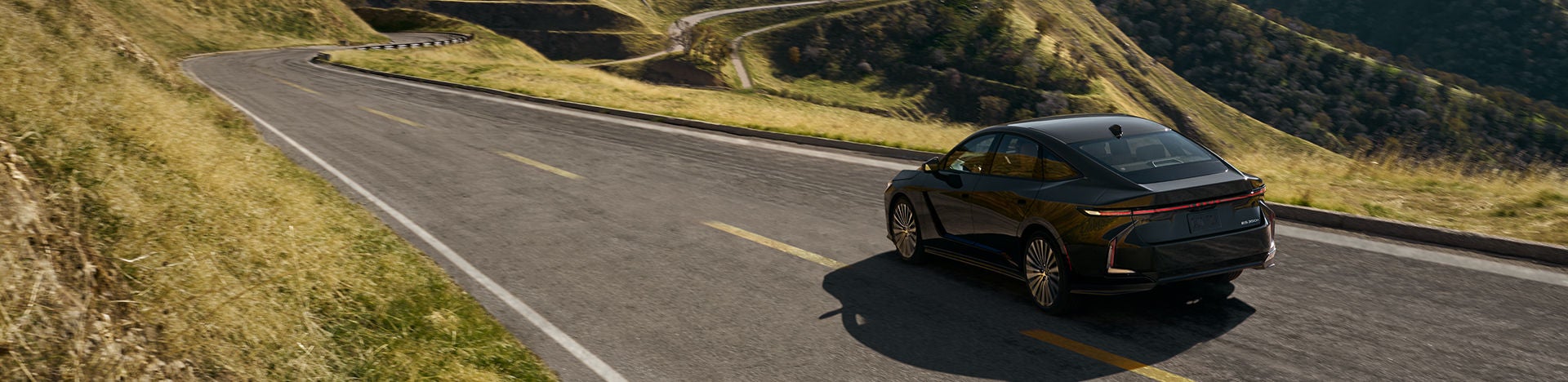 ES 350e Luxury in Caviar exterior color with optional 21-inch alloy wheels driving on a mountain road.