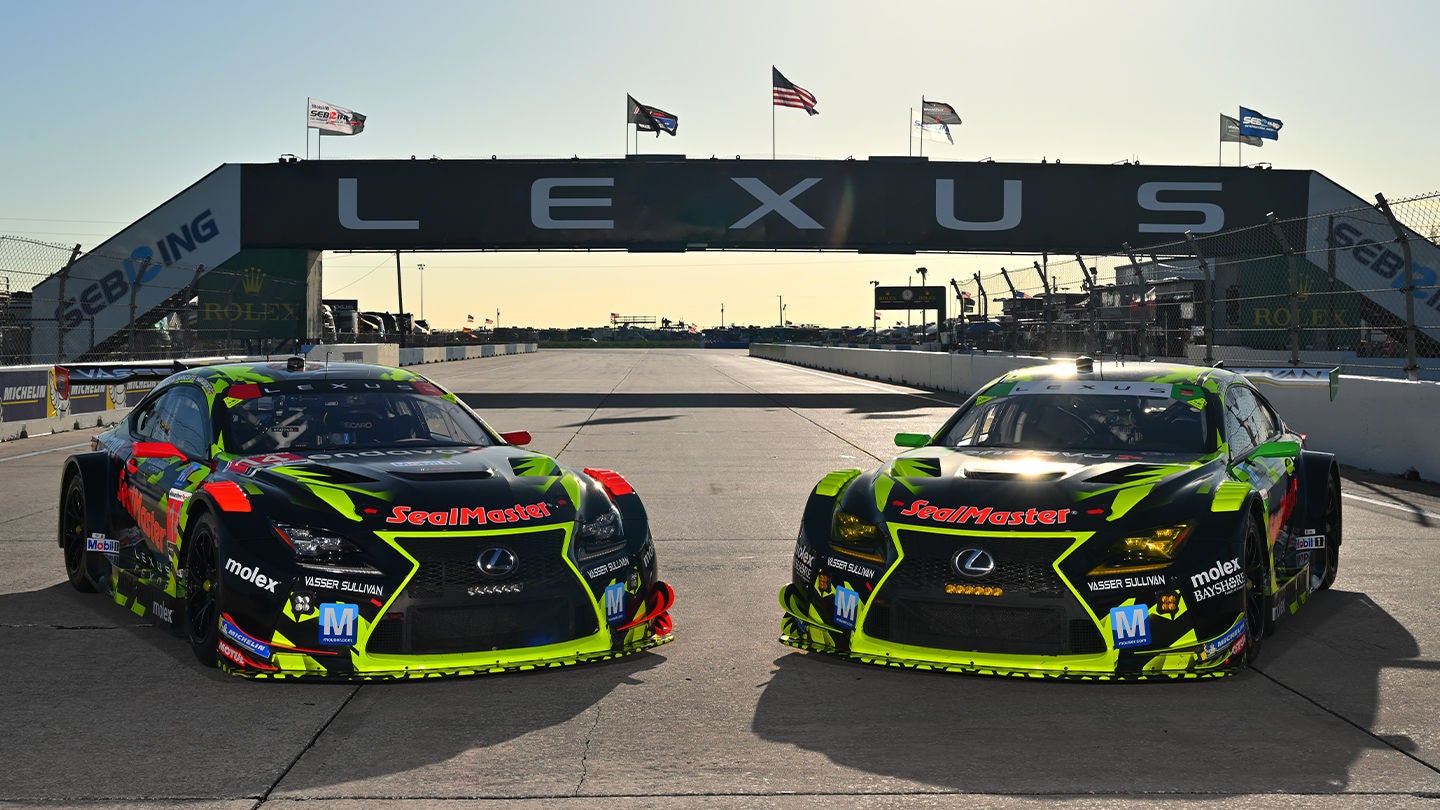 Two black and neon green Lexus RC F GT3 race cars driving on a track at sunset.