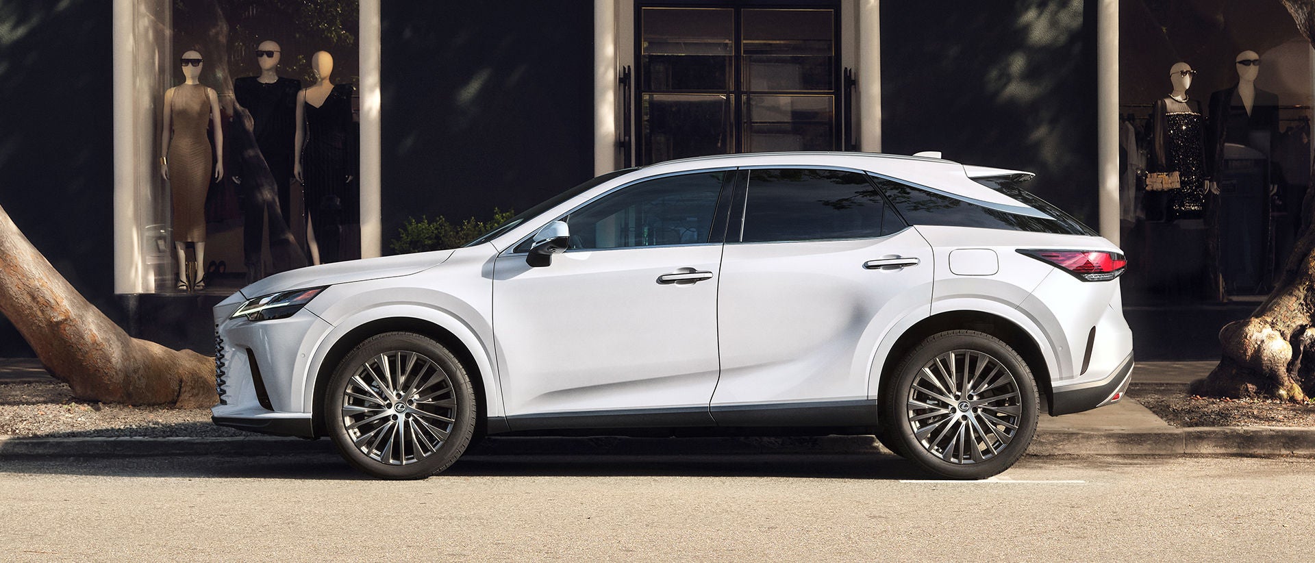 RX 350 Hybrid Luxury all-wheel drive shown in Ultra White and parked outside a stylish clothing store.